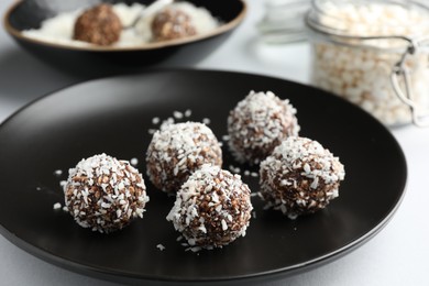 Photo of Tasty chocolate candies with coconut flakes on white table, closeup