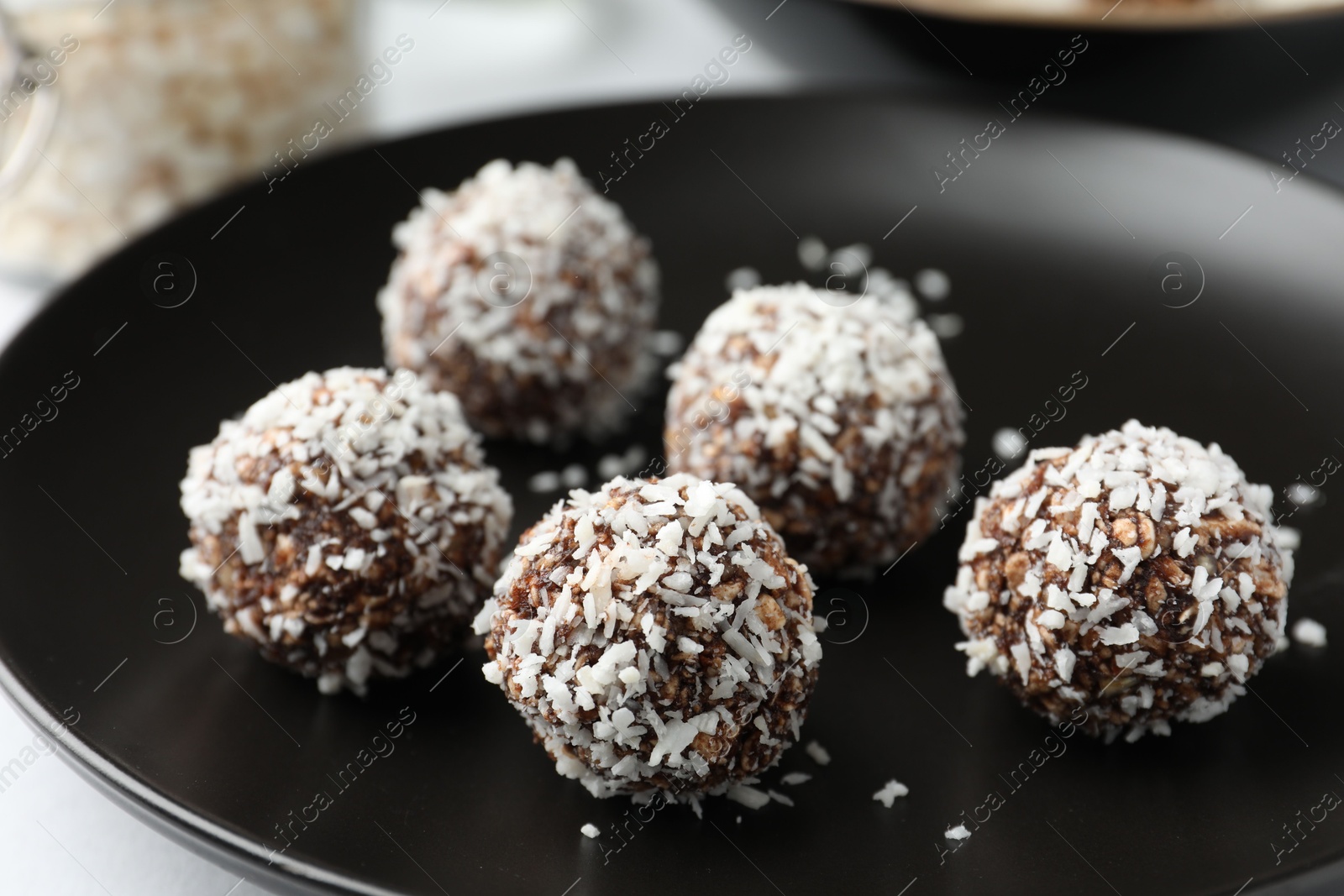 Photo of Tasty chocolate candies with coconut flakes on white table, closeup
