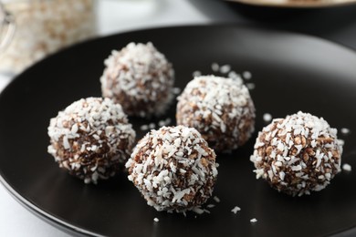 Photo of Tasty chocolate candies with coconut flakes on white table, closeup