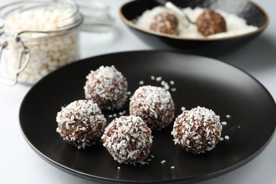 Photo of Tasty chocolate candies with coconut flakes on white table, closeup