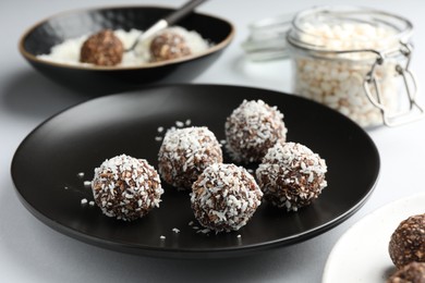 Photo of Tasty chocolate candies with coconut flakes on white table, closeup