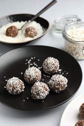 Photo of Tasty chocolate candies with coconut flakes on white table, closeup