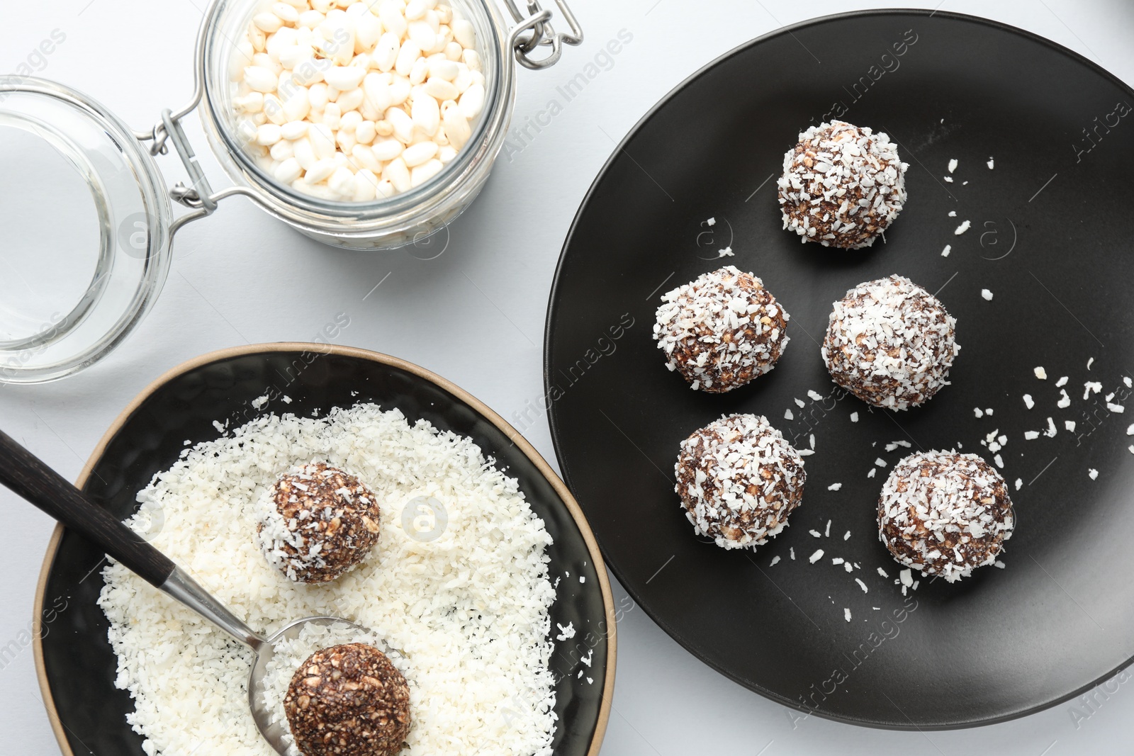 Making tasty chocolate candies with nuts and coconut flakes at white table, flat lay Photo of Making tasty chocolate candies with nuts and coconut flakes at white table, flat lay