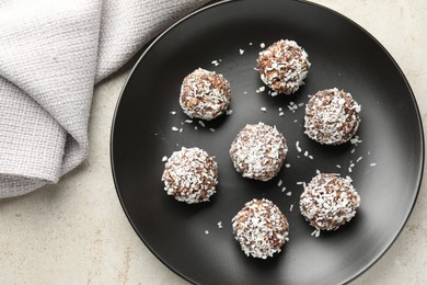 Photo of Tasty chocolate candies with coconut flakes on light table, top view