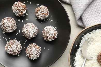Photo of Tasty chocolate candies with coconut flakes on light table, flat lay