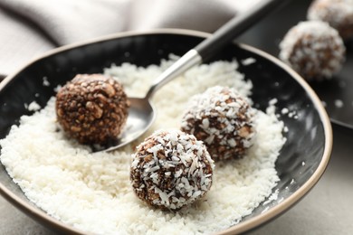 Photo of Making tasty chocolate candies with nuts and coconut flakes at light table, closeup