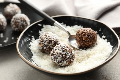 Photo of Making tasty chocolate candies with nuts and coconut flakes at light table, closeup
