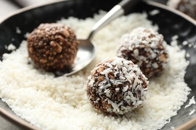 Photo of Making tasty chocolate candies with nuts and coconut flakes at light table, closeup