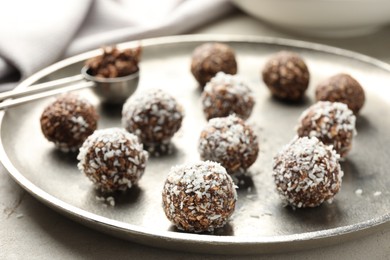 Photo of Tasty chocolate candies with nuts and coconut flakes on light table, closeup