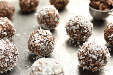 Photo of Tasty chocolate candies with nuts and coconut flakes on grey table, closeup