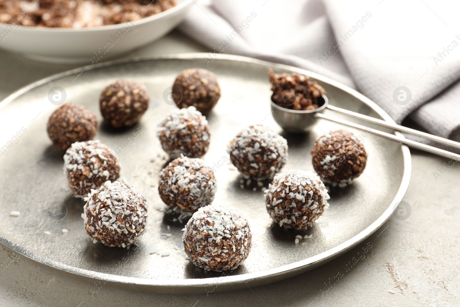 Photo of Tasty chocolate candies with nuts and coconut flakes on light table, closeup