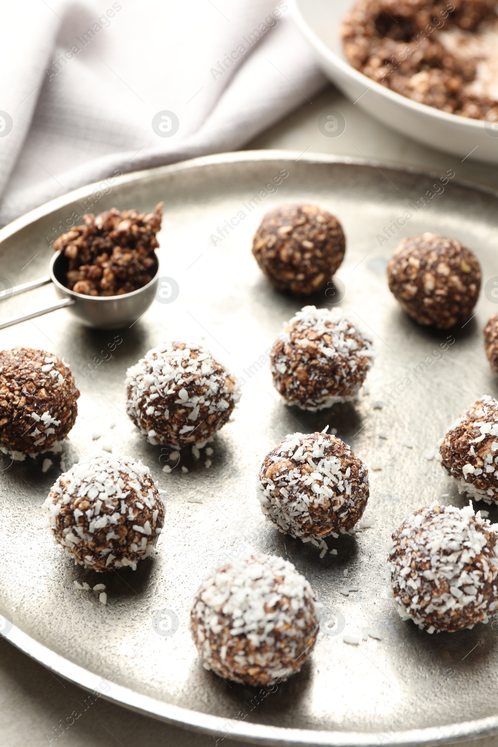 Photo of Tasty chocolate candies with nuts and coconut flakes on light table, closeup
