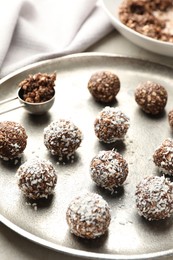 Photo of Tasty chocolate candies with nuts and coconut flakes on light table, closeup