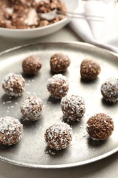 Photo of Tasty chocolate candies with nuts and coconut flakes on light table, closeup