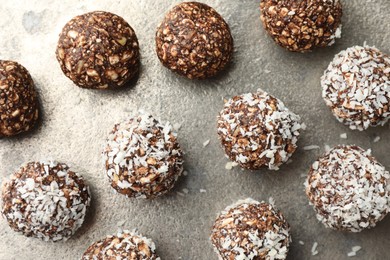 Photo of Tasty chocolate candies with nuts and coconut flakes on grey table, flat lay