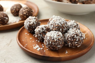 Photo of Tasty chocolate candies with nuts and coconut flakes on light table, closeup