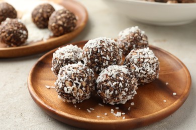 Photo of Tasty chocolate candies with nuts and coconut flakes on light table, closeup