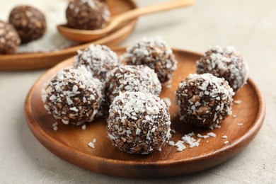 Photo of Tasty chocolate candies with nuts and coconut flakes on light table, closeup
