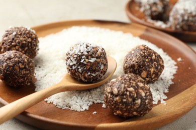 Photo of Making tasty chocolate candies with nuts and coconut flakes at light table, closeup