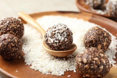 Photo of Making tasty chocolate candies with nuts and coconut flakes at light table, closeup