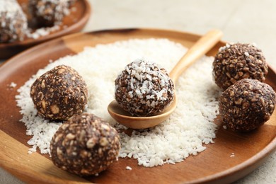 Photo of Making tasty chocolate candies with nuts and coconut flakes at light table, closeup