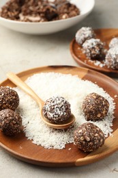 Photo of Making tasty chocolate candies with nuts and coconut flakes at light table, closeup