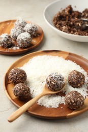 Photo of Making tasty chocolate candies with nuts and coconut flakes at light table, closeup