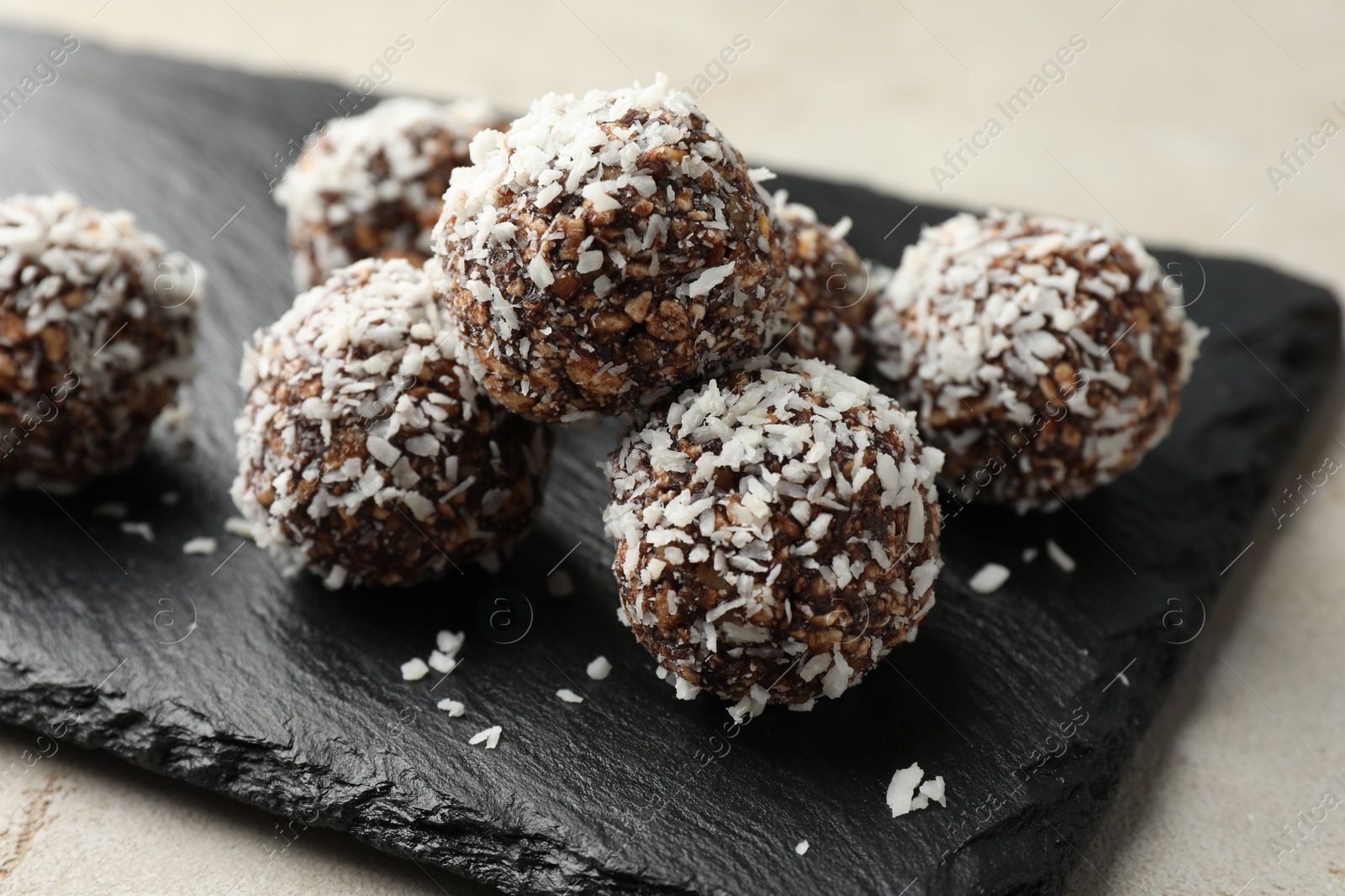 Photo of Tasty chocolate candies with nuts and coconut flakes on light table, closeup