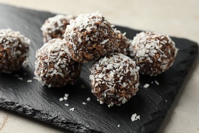 Photo of Tasty chocolate candies with nuts and coconut flakes on light table, closeup