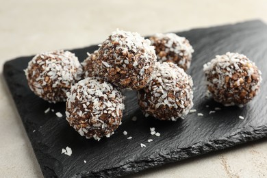 Photo of Tasty chocolate candies with nuts and coconut flakes on light table, closeup