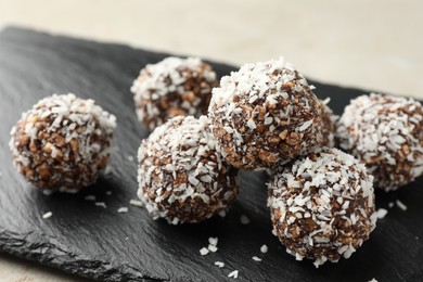Photo of Tasty chocolate candies with nuts and coconut flakes on light table, closeup