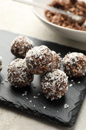 Photo of Tasty chocolate candies with nuts and coconut flakes on light table, closeup
