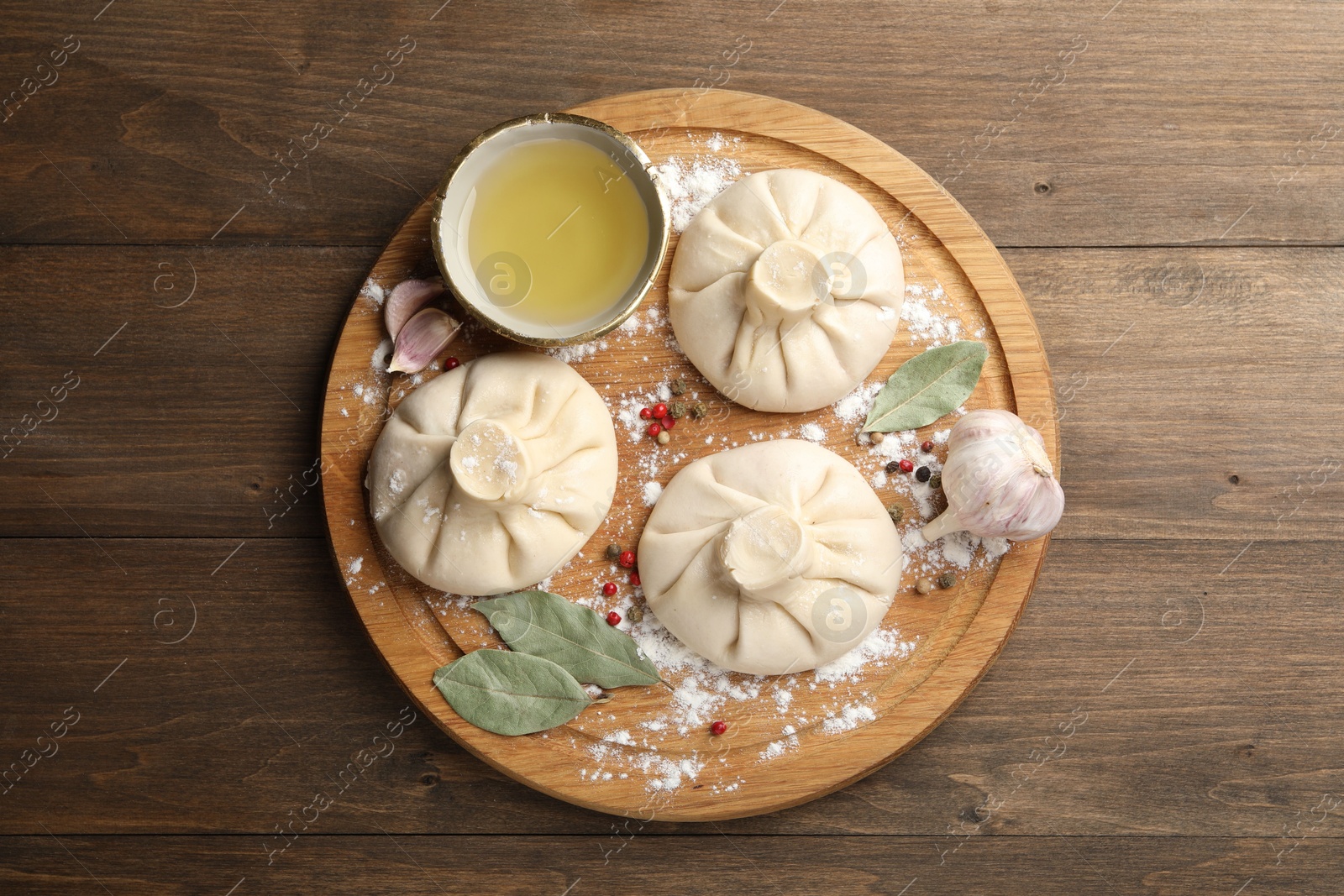 Uncooked khinkalis (dumplings) with peppercorns, flour and bay leaves on wooden table, top view Photo of Uncooked khinkalis (dumplings) with peppercorns, flour and bay leaves on wooden table, top view