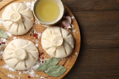 Photo of Uncooked khinkalis (dumplings) with peppercorns, flour and bay leaves on wooden table, top view. Space for text