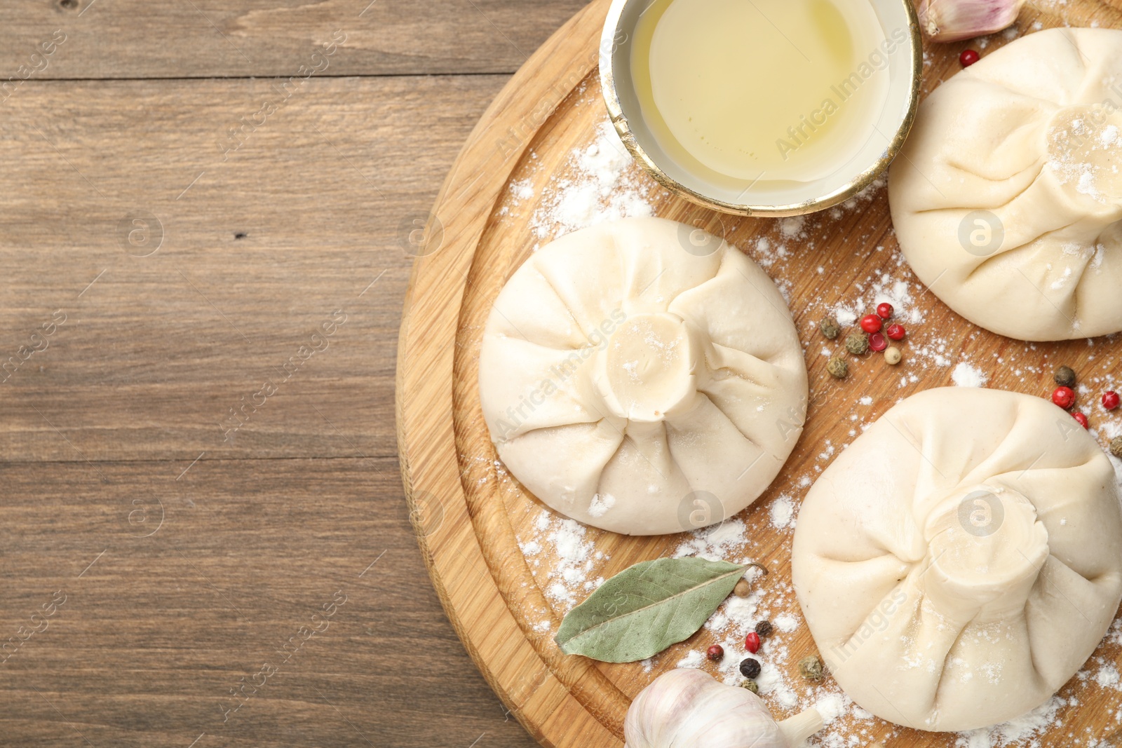 Uncooked khinkalis (dumplings) with peppercorns, flour and bay leaves on wooden table, top view. Space for text Photo of Uncooked khinkalis (dumplings) with peppercorns, flour and bay leaves on wooden table, top view. Space for text