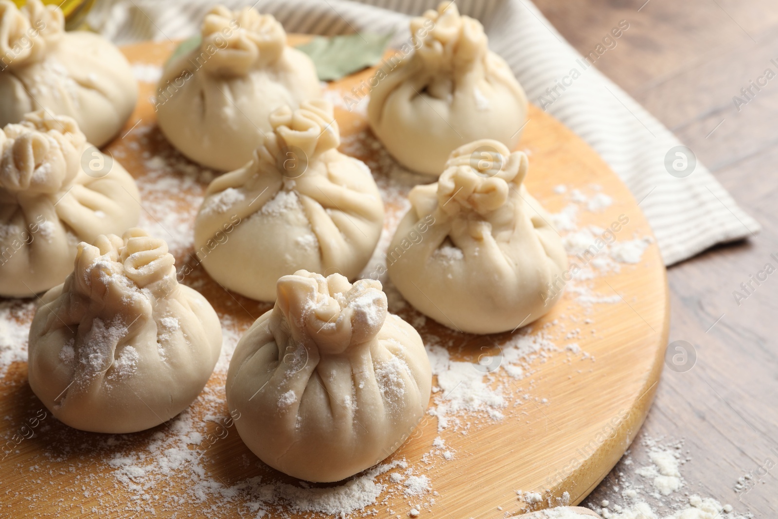 Uncooked khinkalis (dumplings) with flour on wooden table, closeup Photo of Uncooked khinkalis (dumplings) with flour on wooden table, closeup