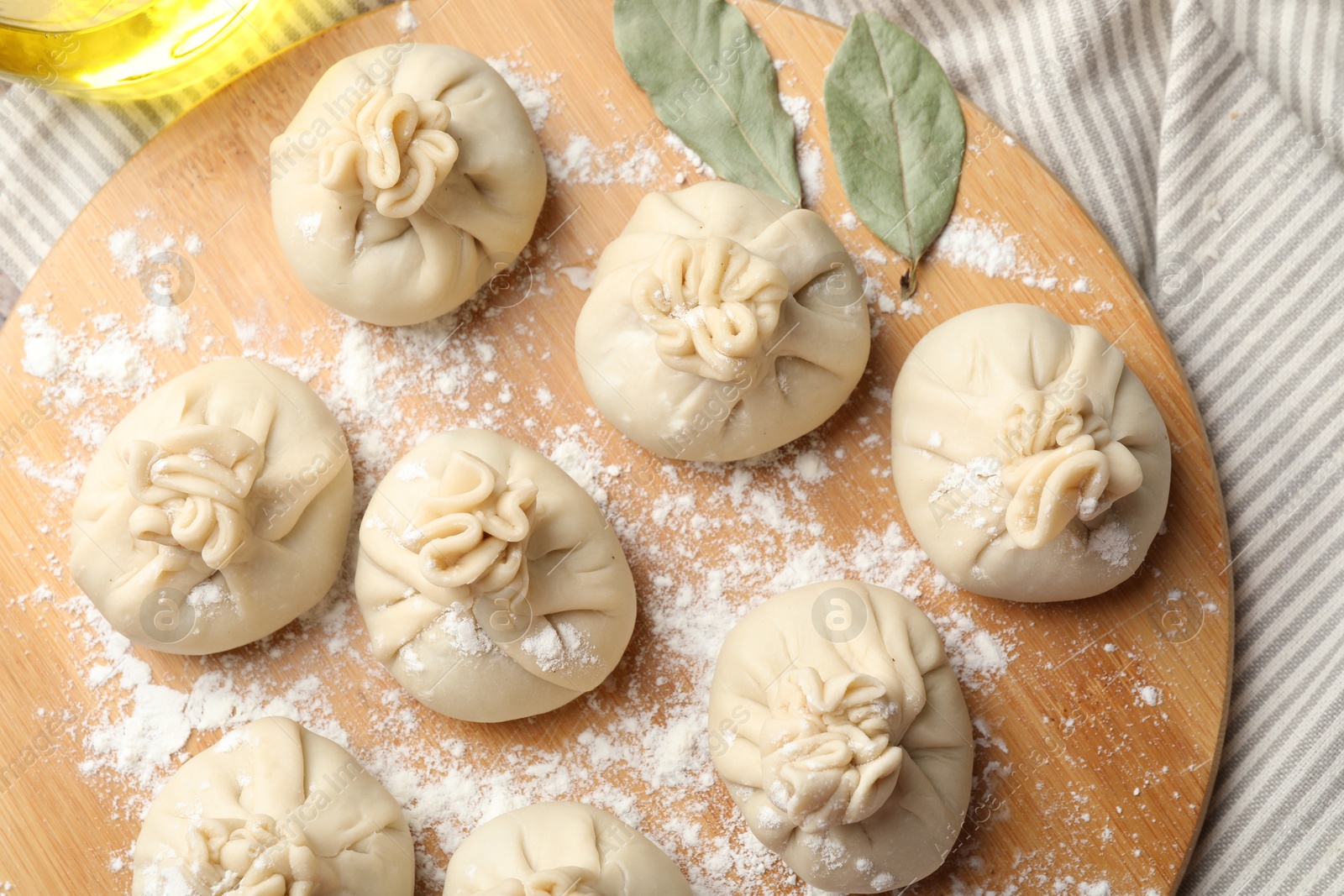 Uncooked khinkalis (dumplings) with flour and bay leaves on table, top view Photo of Uncooked khinkalis (dumplings) with flour and bay leaves on table, top view