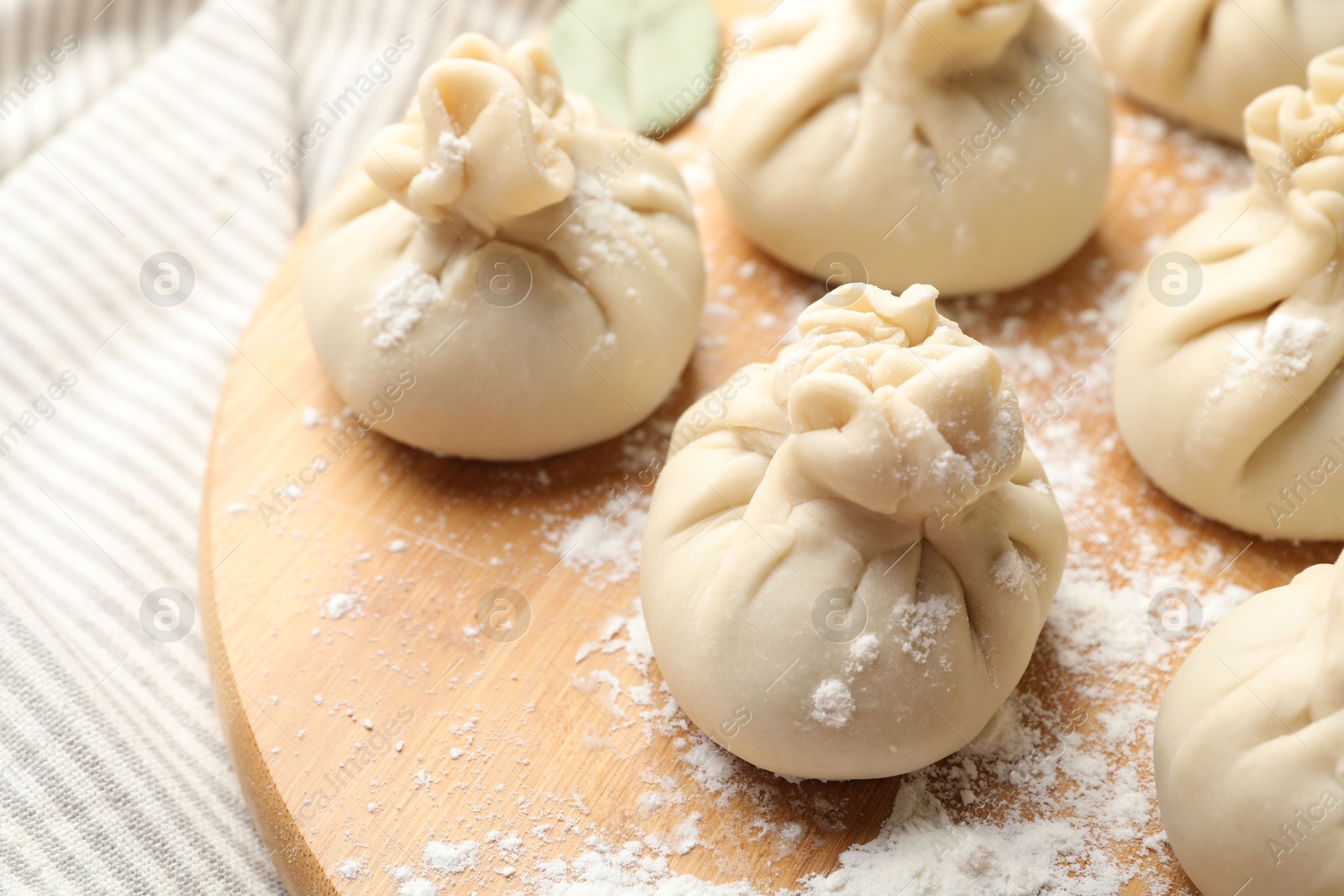 Uncooked khinkalis (dumplings) with flour on table, closeup Photo of Uncooked khinkalis (dumplings) with flour on table, closeup