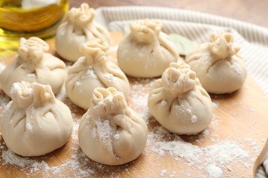 Photo of Uncooked khinkalis (dumplings) with flour on table, closeup