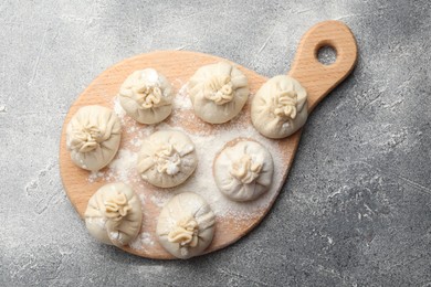 Photo of Uncooked khinkalis (dumplings) with flour on grey table, top view