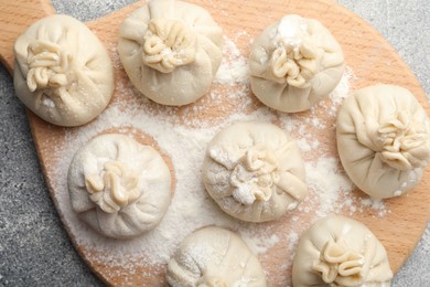 Photo of Uncooked khinkalis (dumplings) with flour on grey table, top view
