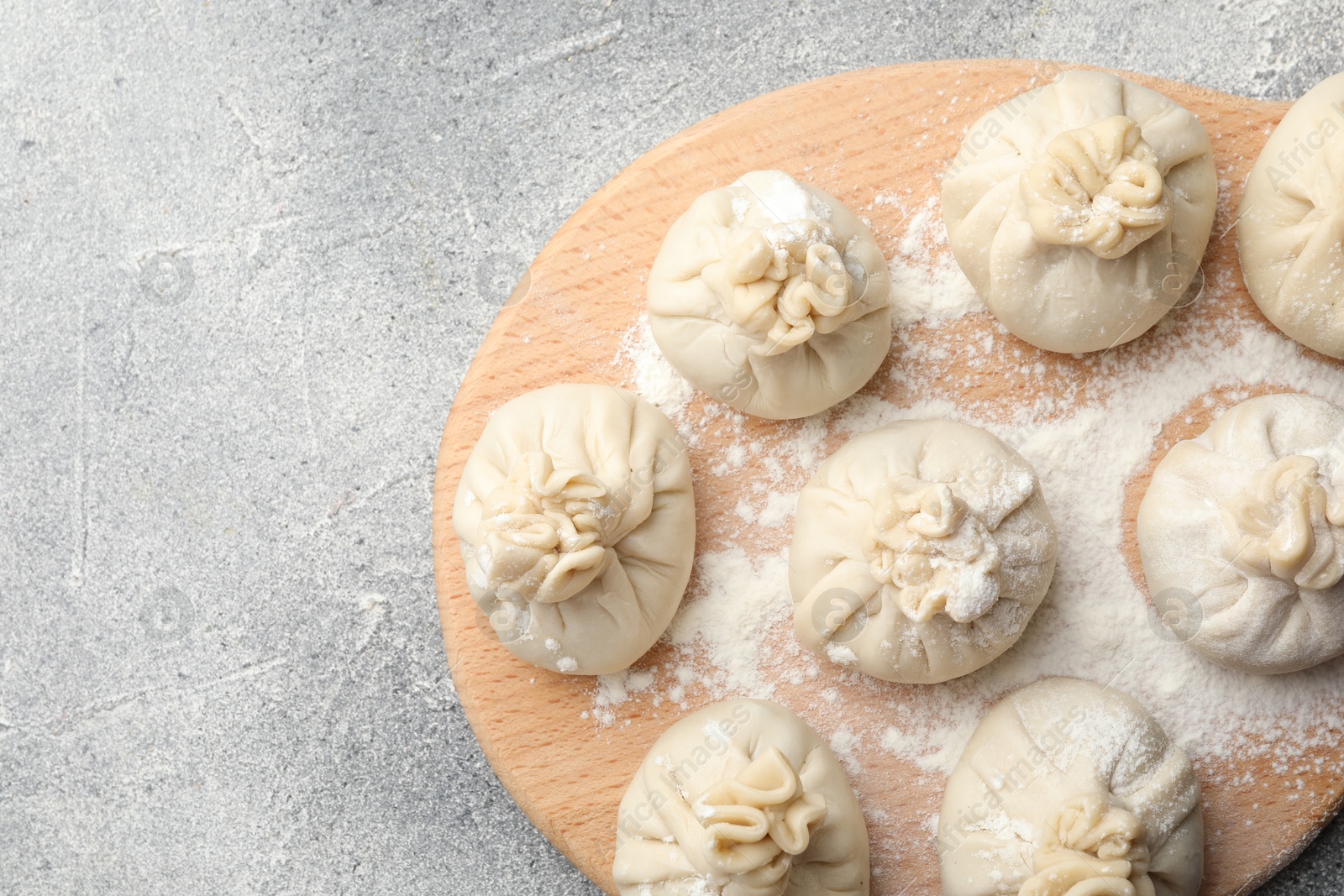 Uncooked khinkalis (dumplings) with flour on grey table, top view. Space for text Photo of Uncooked khinkalis (dumplings) with flour on grey table, top view. Space for text