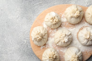 Photo of Uncooked khinkalis (dumplings) with flour on grey table, top view. Space for text