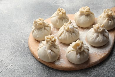 Photo of Uncooked khinkalis (dumplings) with flour on grey table