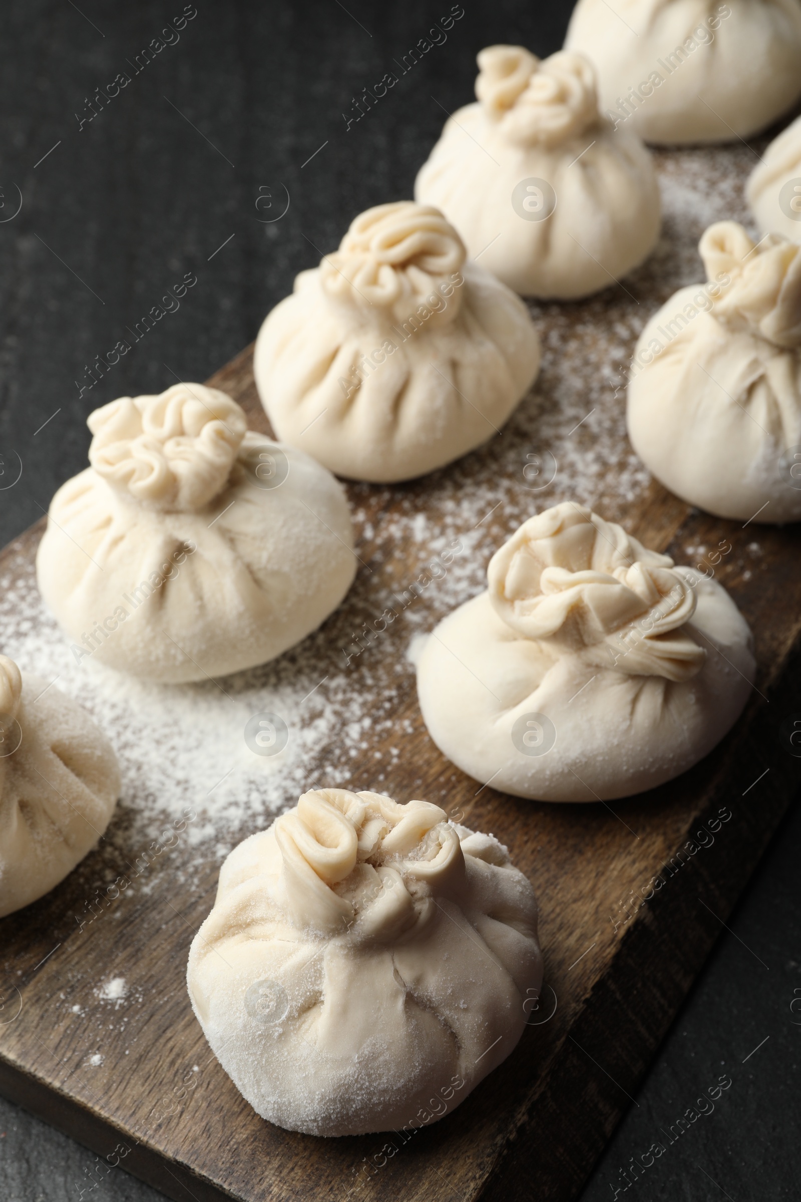 Uncooked khinkalis (dumplings) with flour on black table, closeup Photo of Uncooked khinkalis (dumplings) with flour on black table, closeup