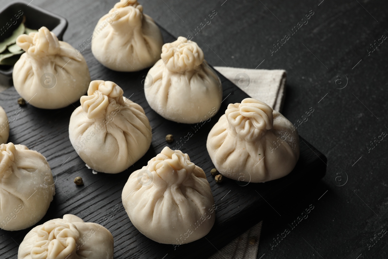 Uncooked khinkalis (dumplings) with peppercorns on black table, closeup Photo of Uncooked khinkalis (dumplings) with peppercorns on black table, closeup