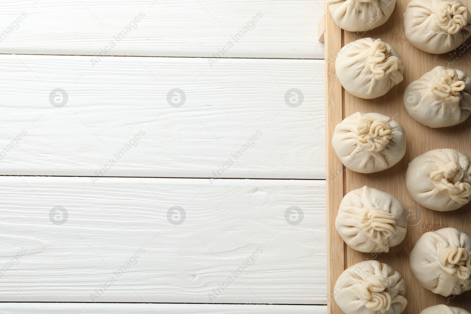 Uncooked khinkalis (dumplings) on white wooden table, top view. Space for text Photo of Uncooked khinkalis (dumplings) on white wooden table, top view. Space for text