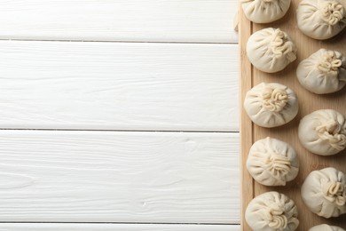 Photo of Uncooked khinkalis (dumplings) on white wooden table, top view. Space for text