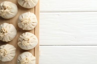 Photo of Uncooked khinkalis (dumplings) on white wooden table, top view. Space for text