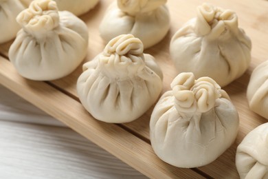 Photo of Uncooked khinkalis (dumplings) on white wooden table, closeup